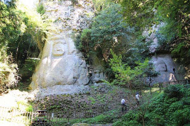 This is the Kumano Magaibutsu Buddha located on the Kunisaki Peninsula in Oita, Japan. Two large Magaibutsu are carved into the rock face. Two worshippers are climbing up the mountain path.