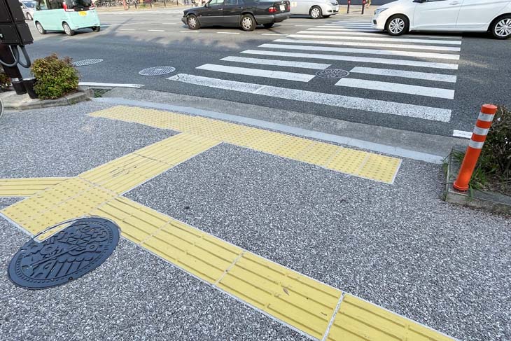 There is a yellow block on the sidewalk in front of the crosswalk in Japan. These are called "Braille blocks," which are guides for the visually impaired.