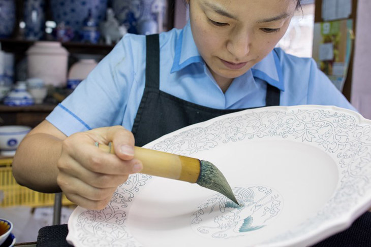 At the workshop of Fukagawa Porcelain, a leading manufacturer of Arita porcelain, a large plate is being painted.