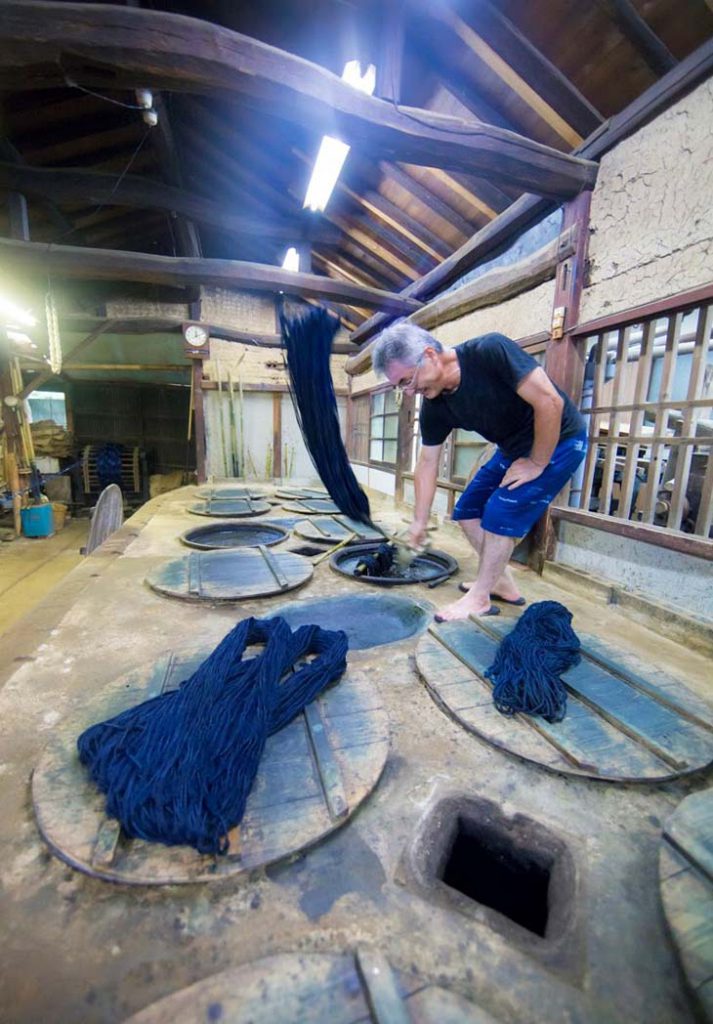 At the Kurume Kasuri workshop, the indigo-dyed threads are being tapped into the hollows between the jars in order to better color them.